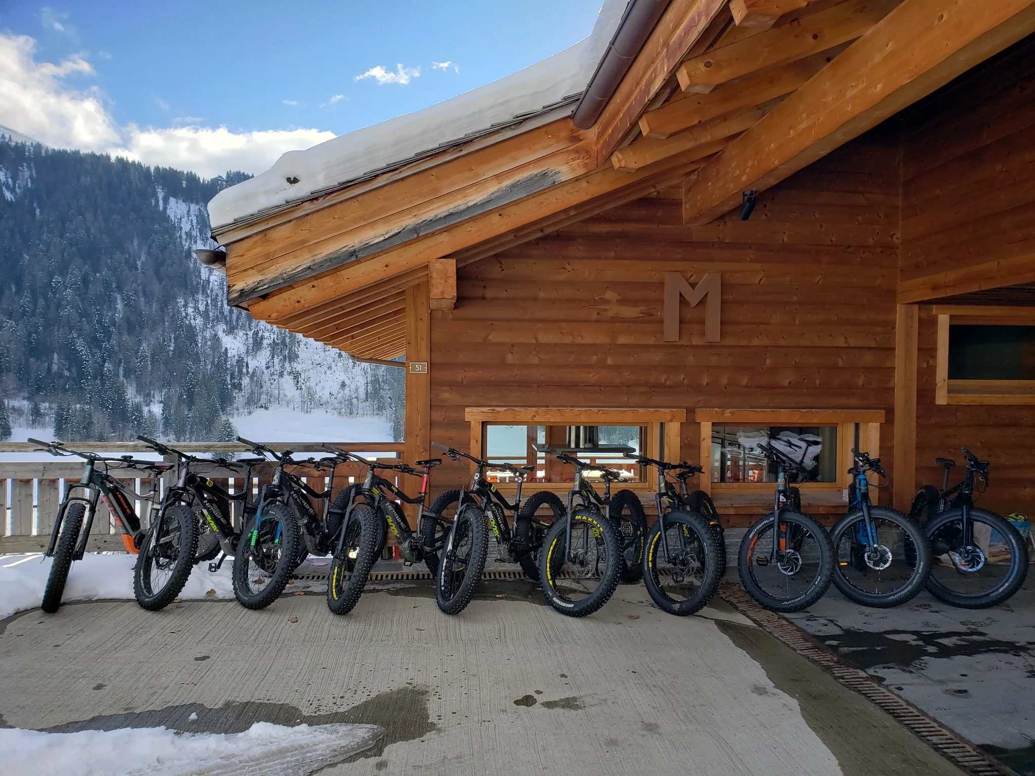 Fatbikes électriques alignés devant un chalet enneigé, prêts pour la balade